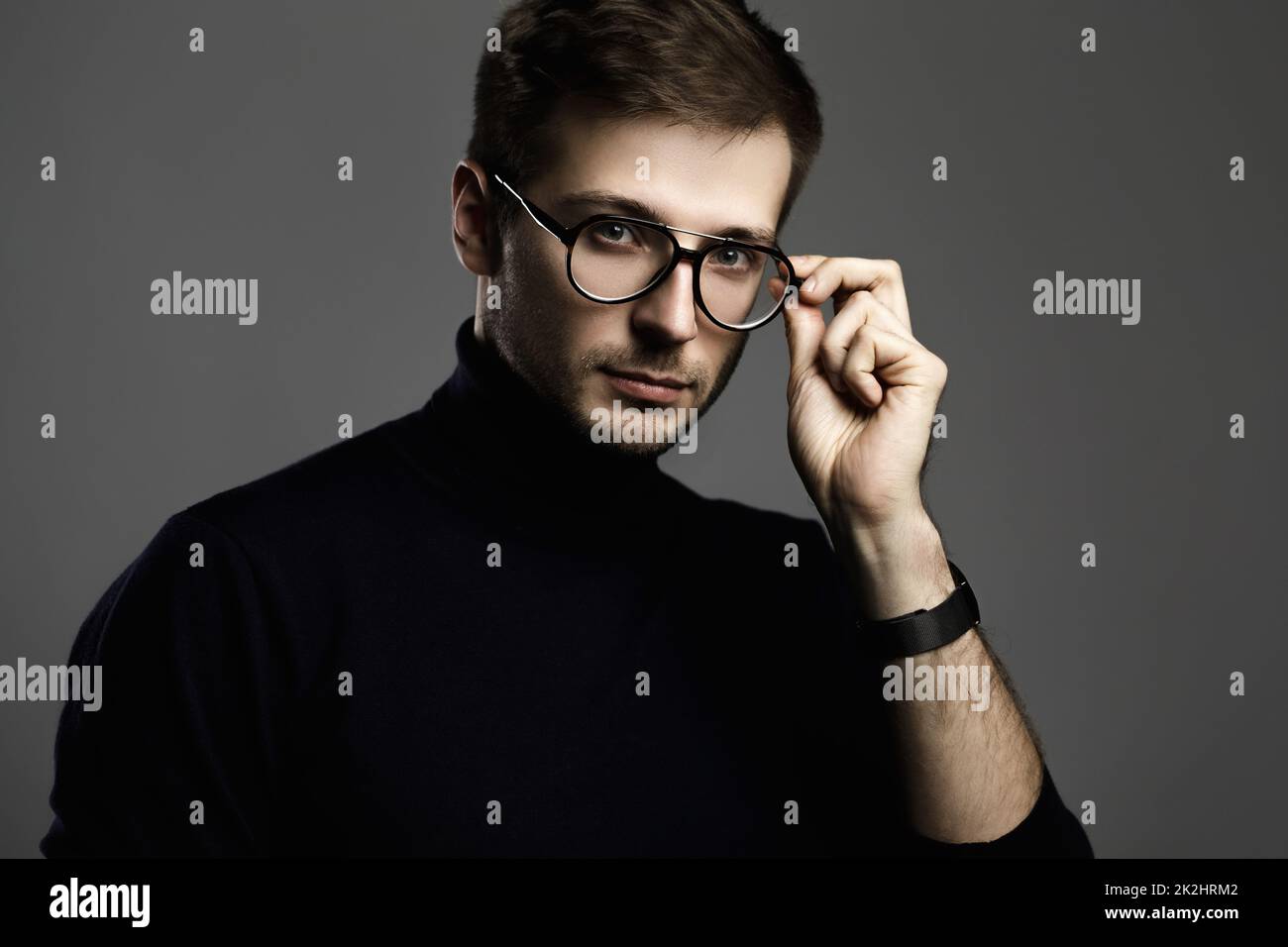 Jeune homme intelligent portant un col de cygne et des lunettes Banque D'Images