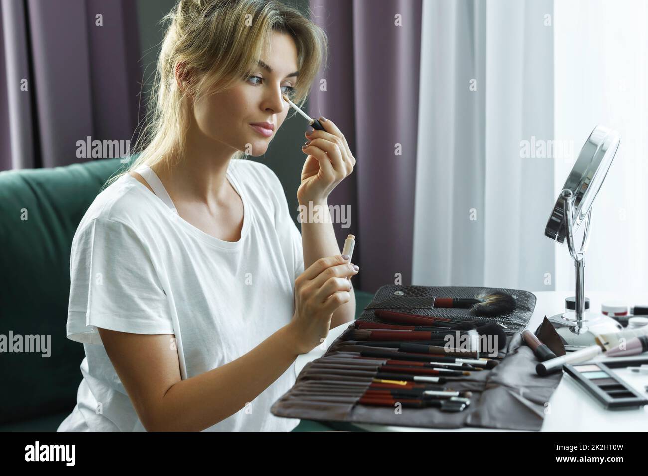 Belle femme applique le correcteur sous ses yeux Banque D'Images