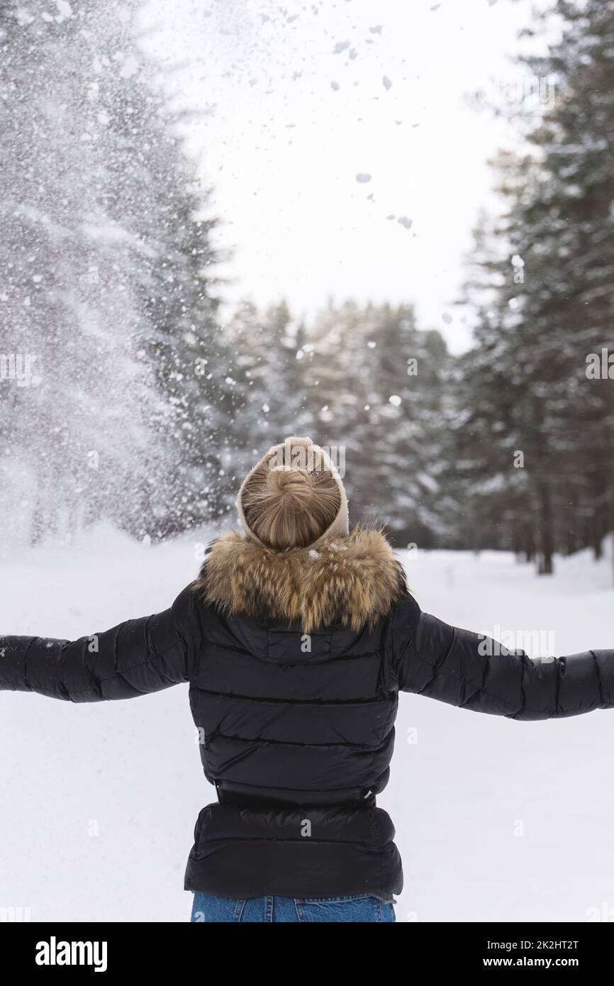 Femme jetant de la neige dans l'air pendant la journée froide d'hiver Banque D'Images