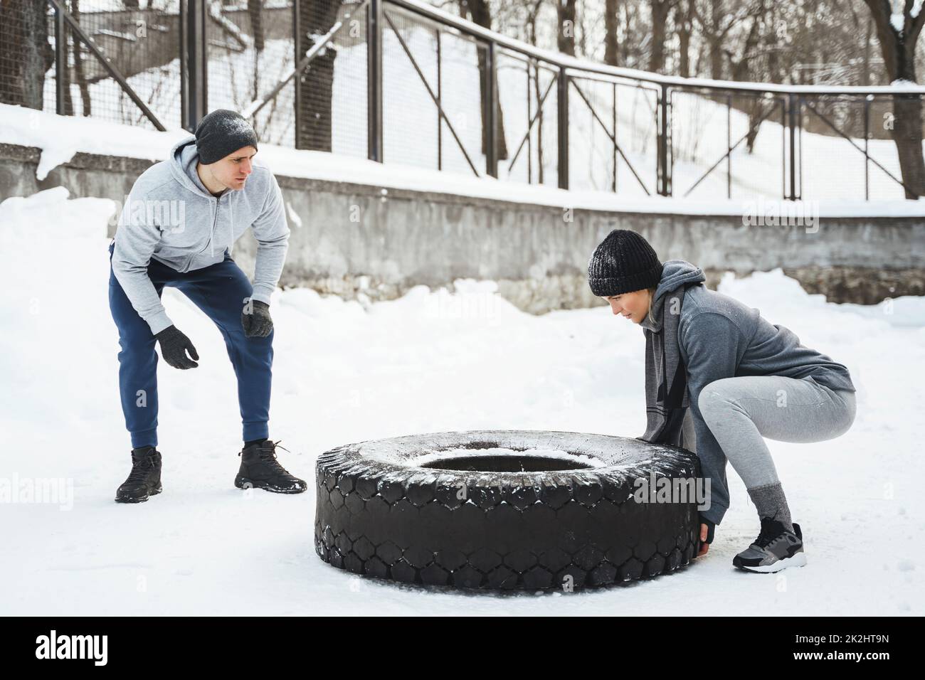 Entraîneur et sa cliente pendant l'entraînement avec un pneu pendant l'hiver froid et la journée enneigée Banque D'Images