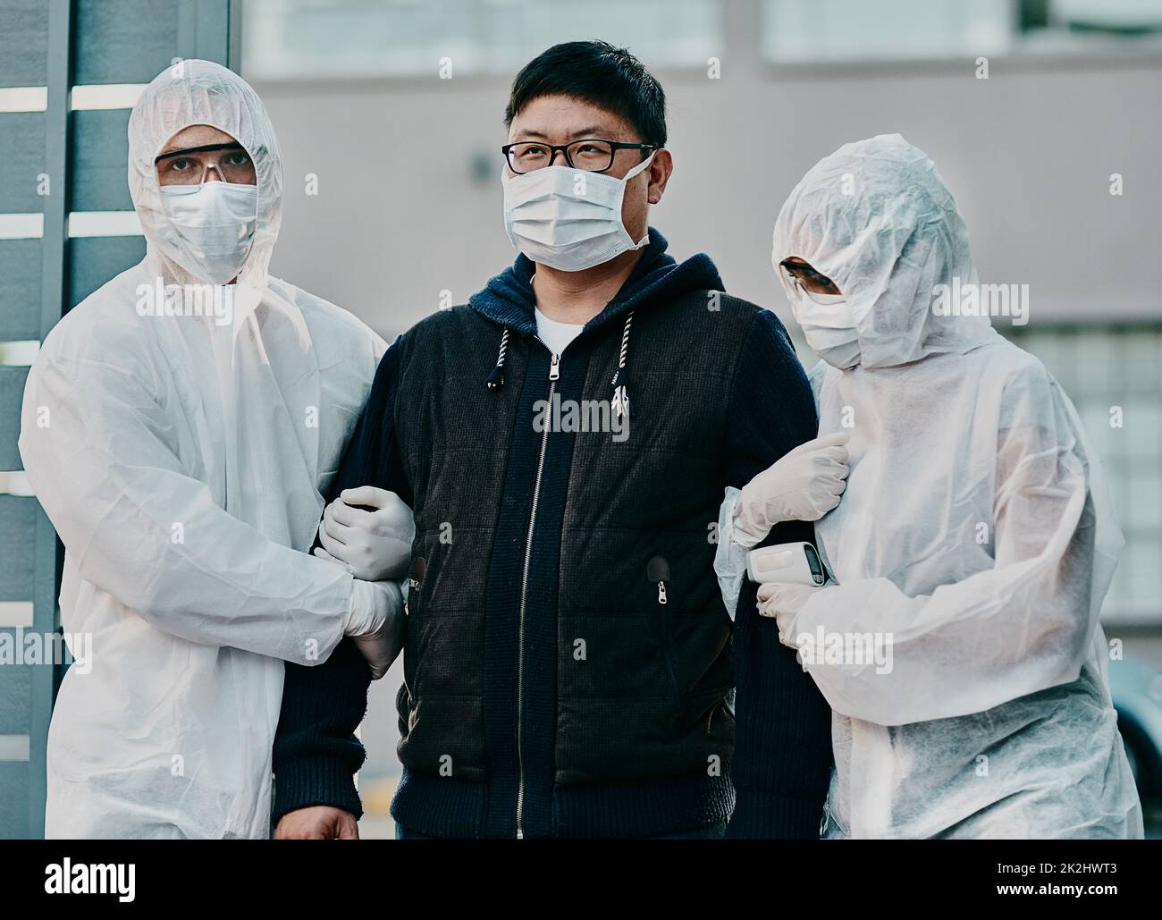 Le traitement commence aujourd'hui.Photo d'un jeune homme qui s'est retiré par des travailleurs de la santé dans des combinaisons de matières dangereuses pendant une épidémie. Banque D'Images