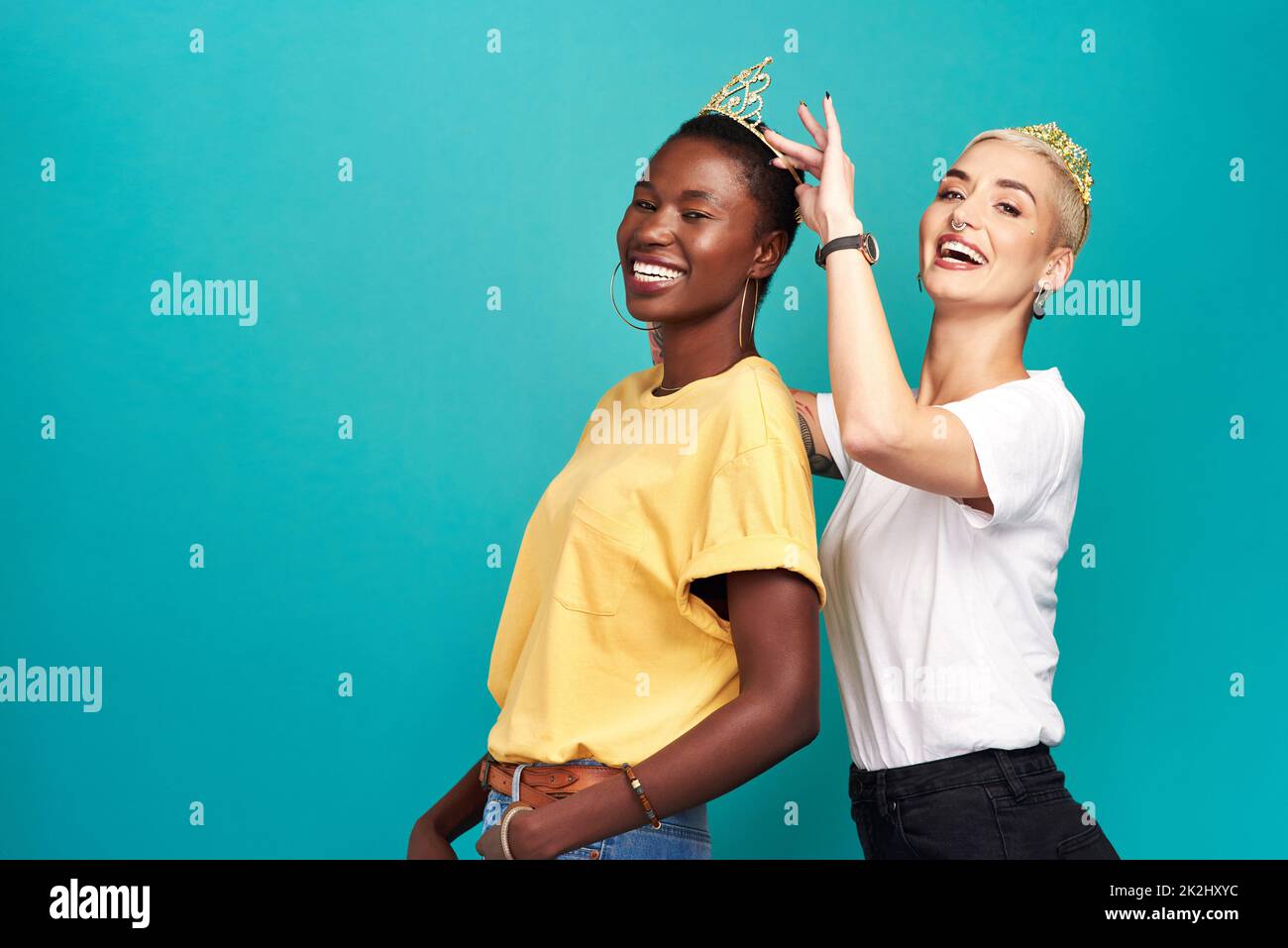 Qui dirige le monde que nous faisons.Studio photo d'une jeune femme mettant une couronne sur son ami sur un fond turquoise. Banque D'Images