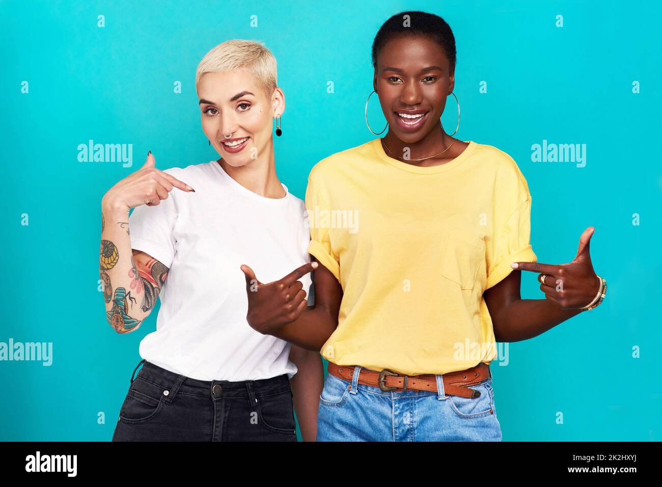 Dites votre vérité.Photo en studio de deux jeunes femmes confiantes montrant leurs t-shirts sur fond turquoise. Banque D'Images