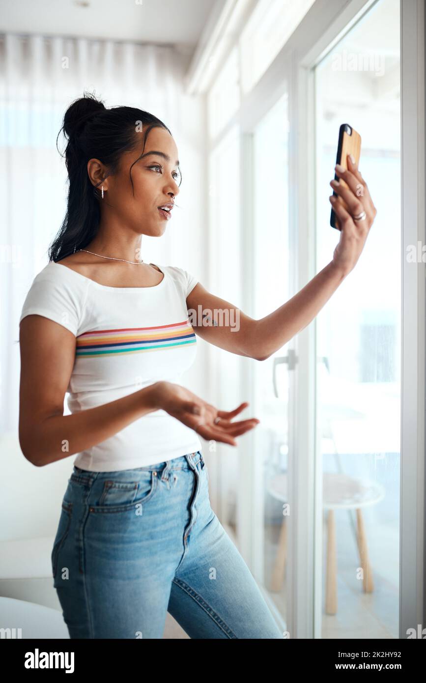 Toujours créer du contenu pertinent.Photo rognée d'une jeune blogueur attrayante debout dans sa maison et utilisant son téléphone portable pour enregistrer un vlog. Banque D'Images