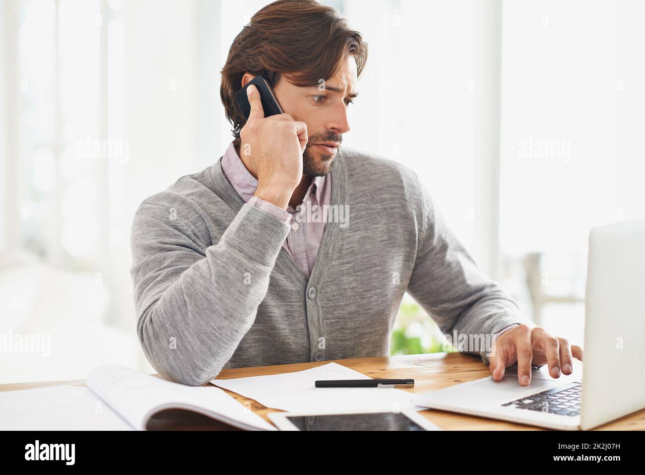 Connecté au monde.Un beau homme d'affaires parlant sur son mobile à son bureau. Banque D'Images