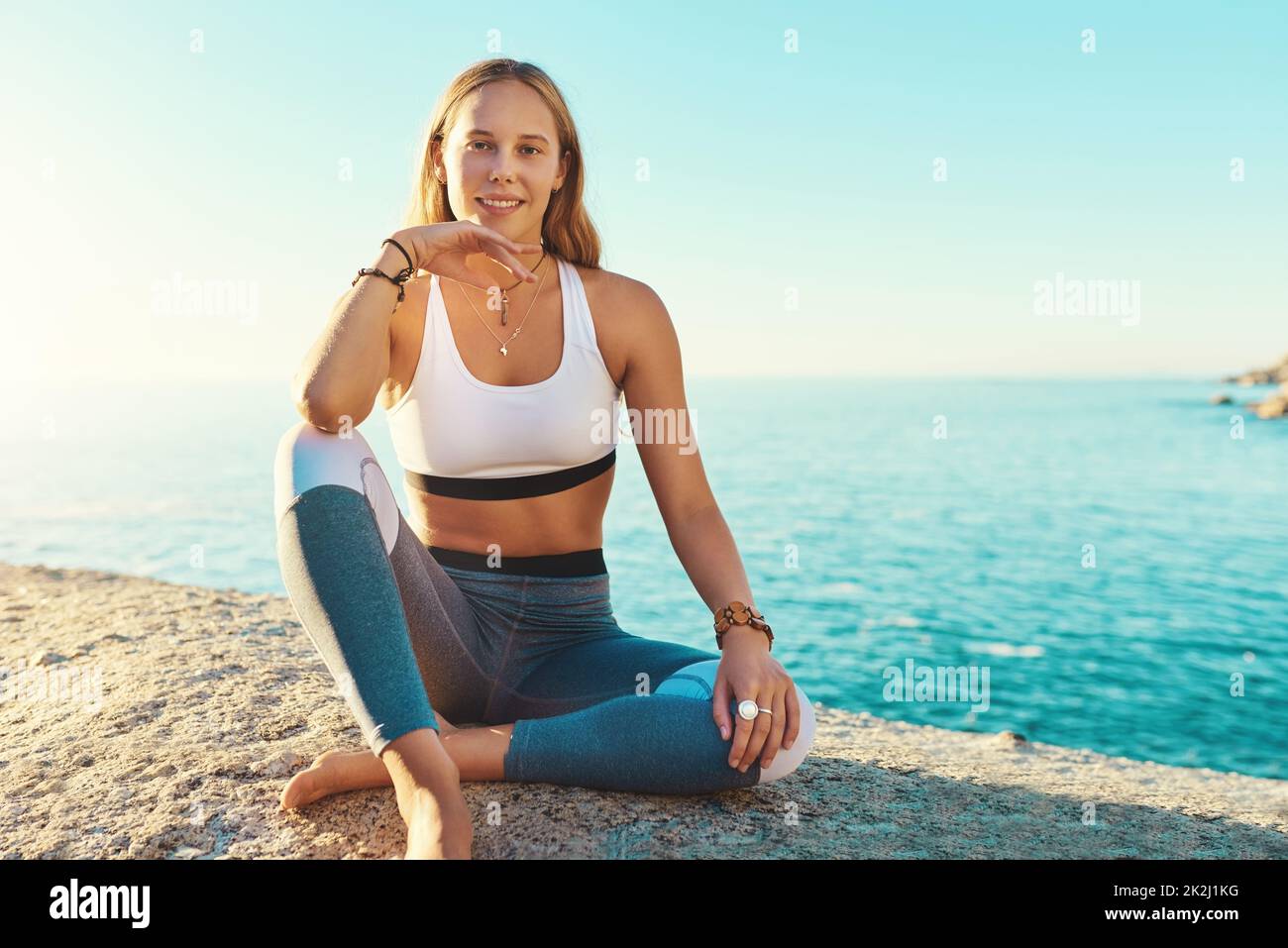 Le yoga est mon endroit heureux.Portrait d'une belle jeune femme assise sur la plage pour sa séance de yoga. Banque D'Images