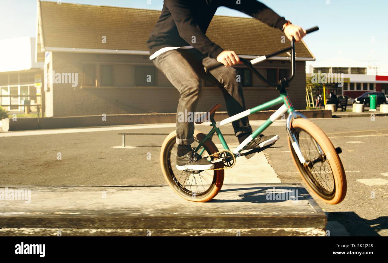 Prenez la route.Coupe courte d'un cycliste BMX masculin méconnu faisant des tours à l'extérieur. Banque D'Images