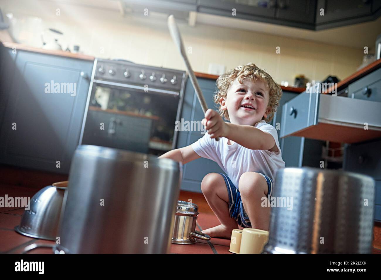 Vous pouvez l'appeler bruit, mais les enfants l'appellent amusant. Photo d'un adorable petit garçon jouant des tambours sur un ensemble de pots dans la cuisine. Banque D'Images