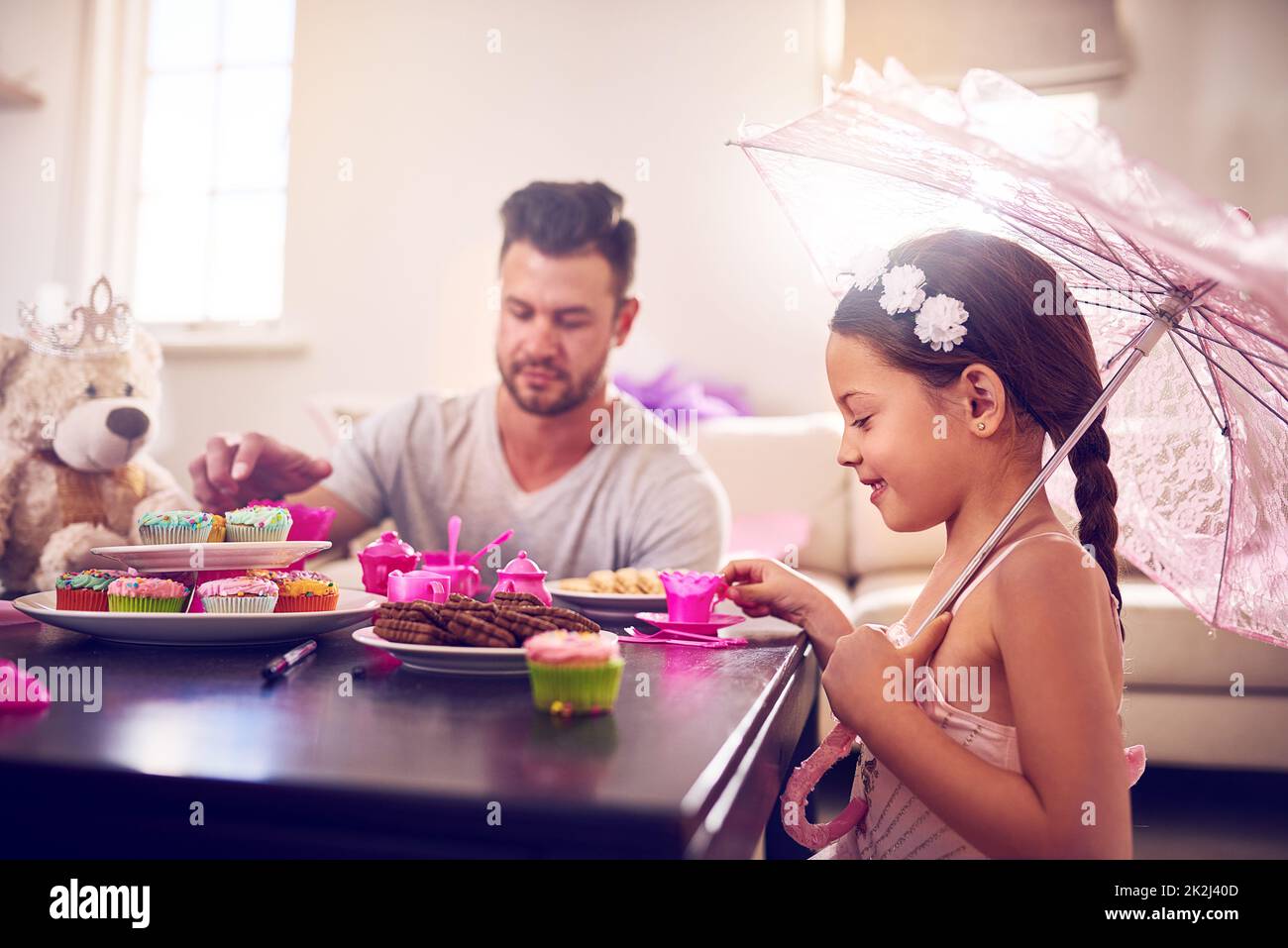 Chaque grand souvenir d'enfance inclut une fête de thé royal. Photo d'un père et de sa petite fille ayant une fête de thé ensemble à la maison. Banque D'Images