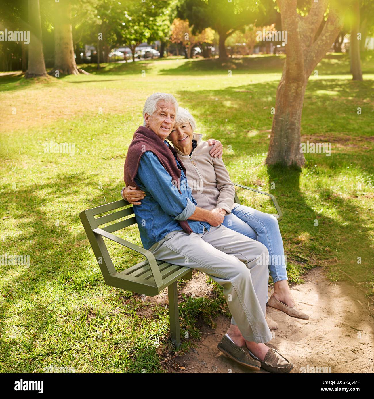 Ils connaissent les voies de l'amour.Portrait d'un heureux couple senior assis sur un banc de parc. Banque D'Images