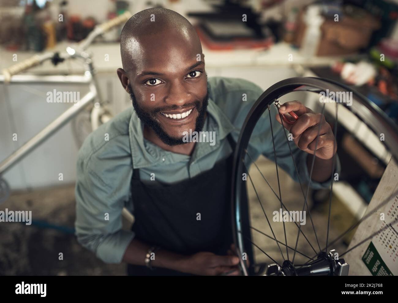 Ajoutez une touche magique. Photo en grand angle d'un beau jeune homme debout seul dans son atelier et réparant une roue de vélo. Banque D'Images