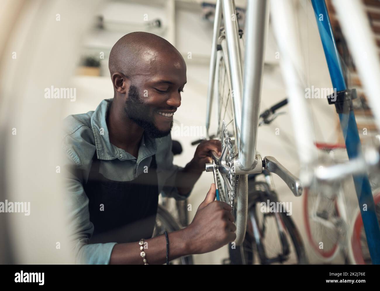 Les vélos sont ma passion. Photo d'un beau jeune homme qui s'est accroupi dans son atelier et a réparé une roue de vélo. Banque D'Images