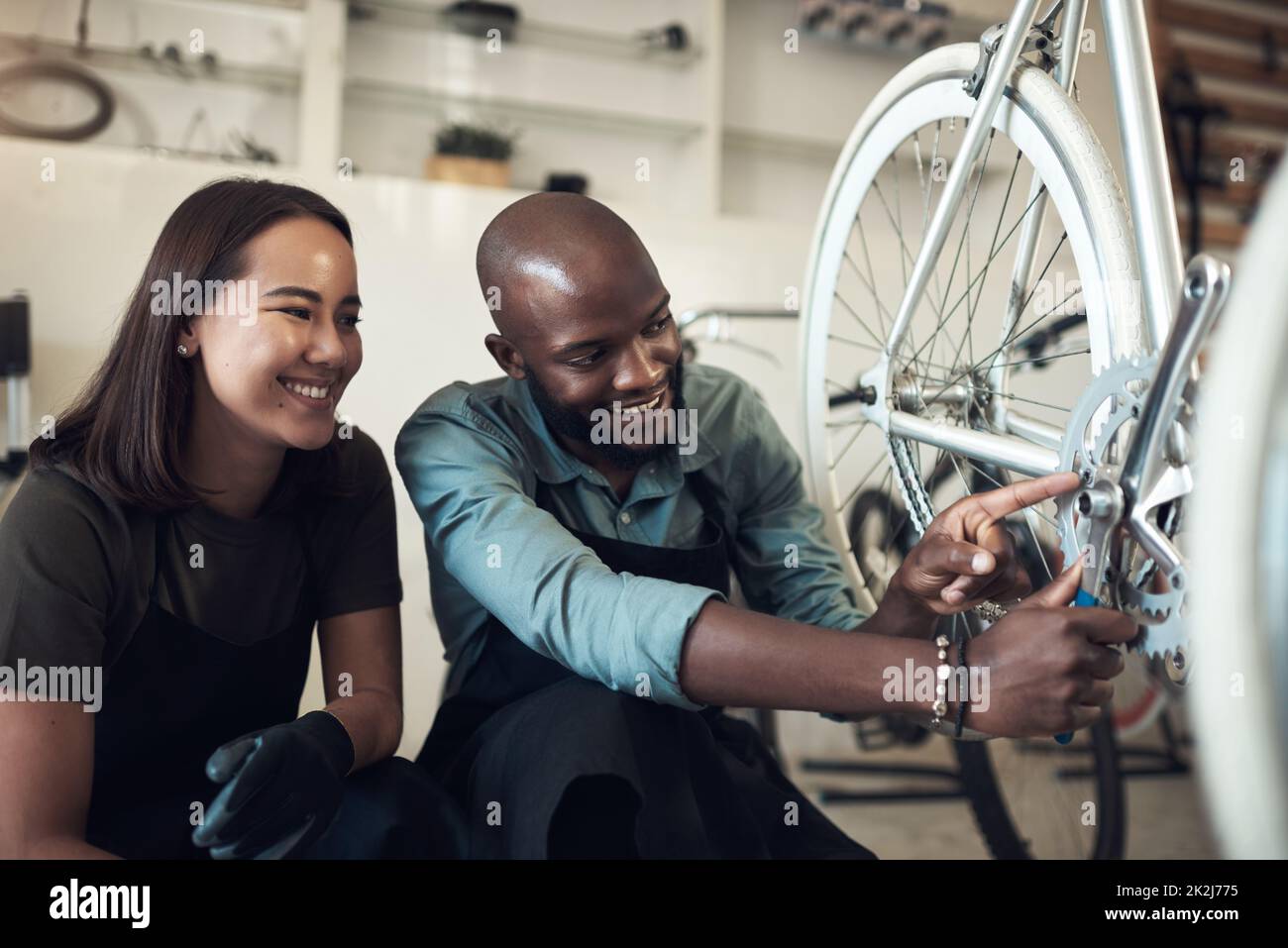 J'ai réparé ça. Photo de deux jeunes propriétaires d'entreprise qui se sont accroués dans leur boutique et ont fixé une roue de vélo. Banque D'Images
