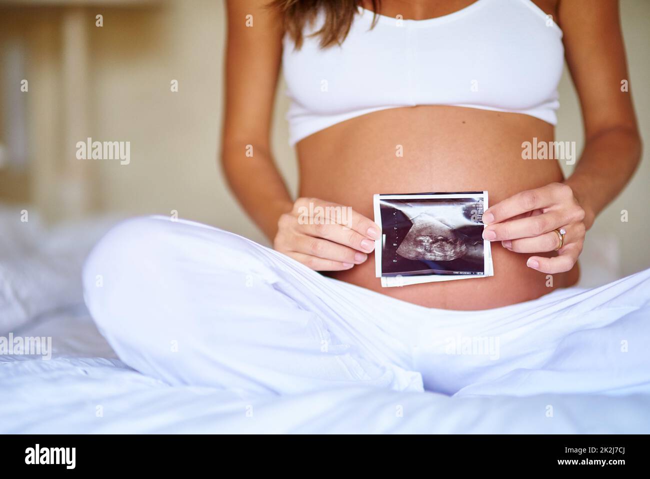 Shes est enthousiaste à l'idée de son petit enfant. Prise de vue d'une femme enceinte tenant une image d'un sonogramme devant son ventre. Banque D'Images