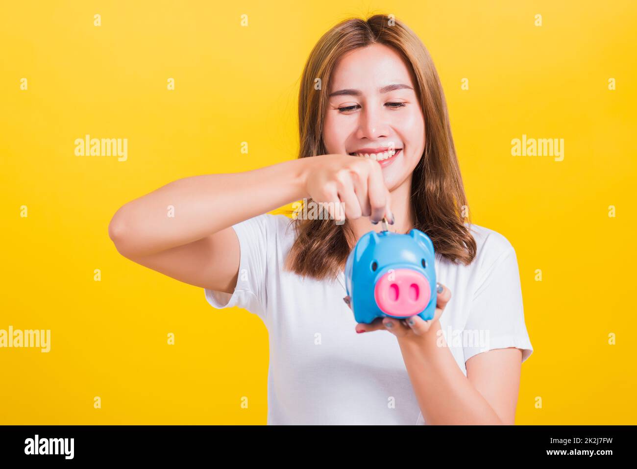 une femme souriante tient la banque de piggy avec beaucoup d'argent Banque D'Images