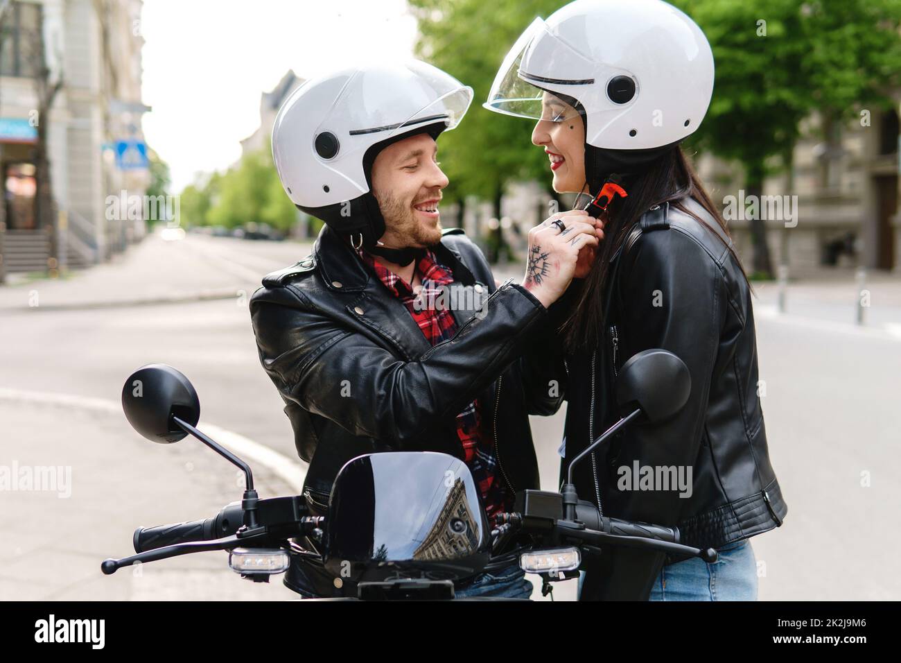 Couple élégant portant un casque de moto avant de monter sur un scooter électrique Banque D'Images