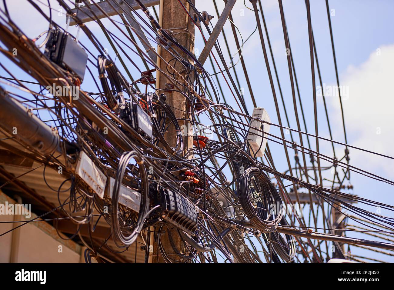 Développement urbain non planifié. Prise de vue de câbles téléphoniques et d'alimentation chaotiques sur un poste en Thaïlande. Banque D'Images