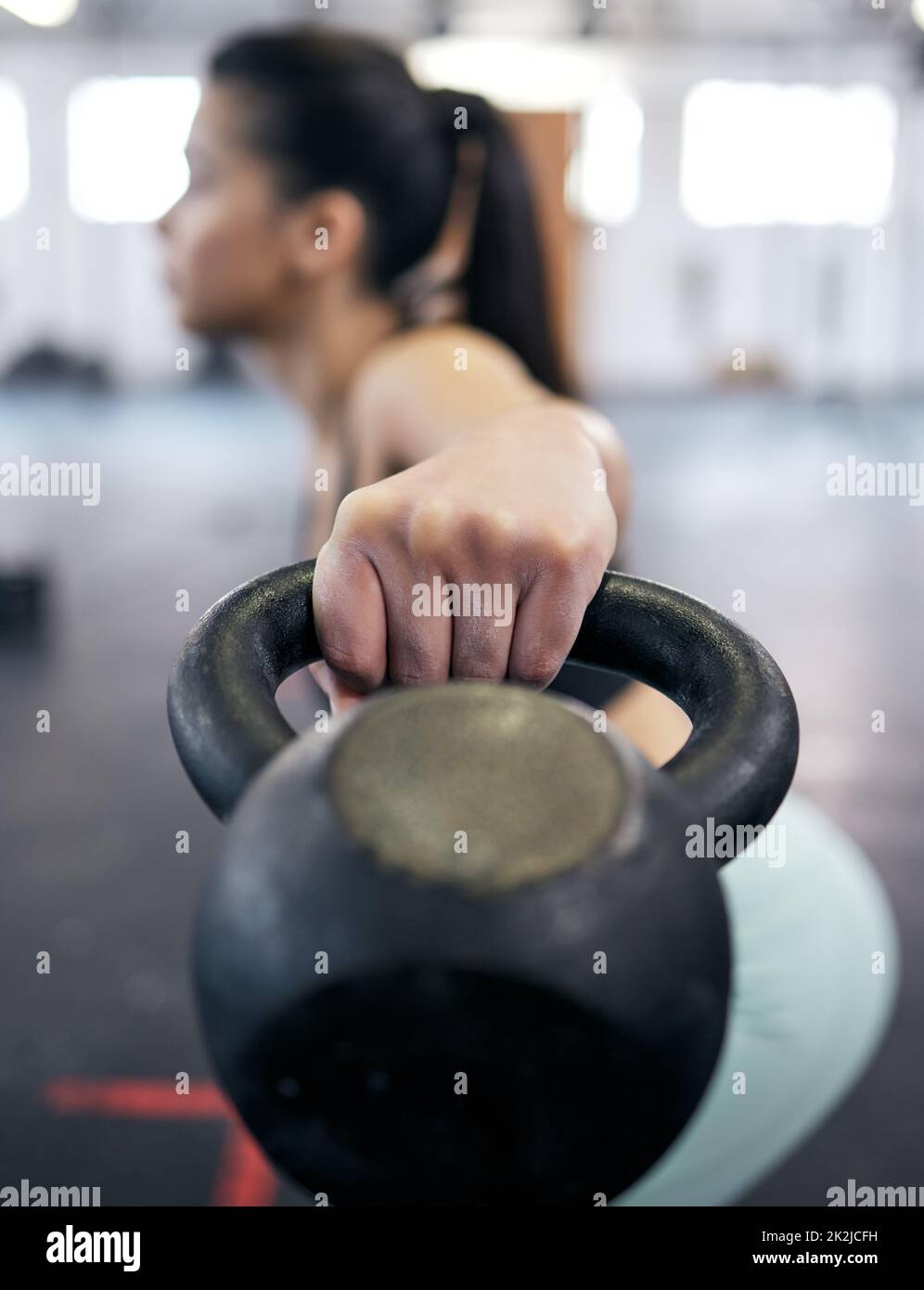 Les muscles tonifiant sont tous dans la technique. Photo d'une jeune femme s'entraîner avec des poids de cloche dans une salle de gym. Banque D'Images