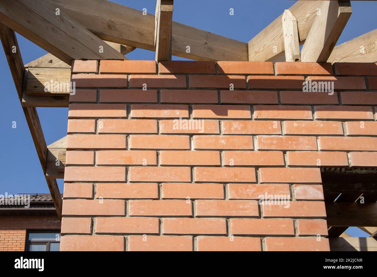 Un bâtiment résidentiel privé en construction avec une structure de toit en bois. Bâtiment en brique non fini en construction, gros plan Banque D'Images