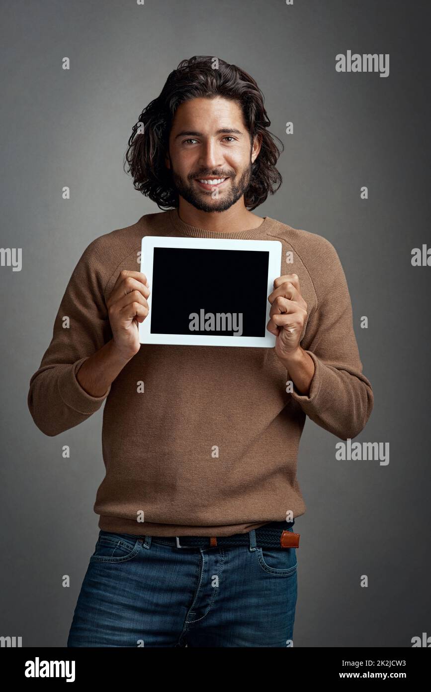 Je suis heureux de vous donner mon soutien. Photo en studio d'un jeune homme charmant tenant une tablette numérique avec un écran vierge sur fond gris. Banque D'Images