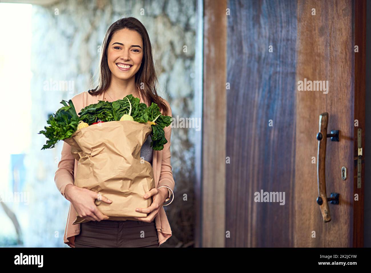 Commencer mon nouveau régime. Portrait d'une jeune femme attirante qui arrive à la maison avec un sac plein de provisions. Banque D'Images