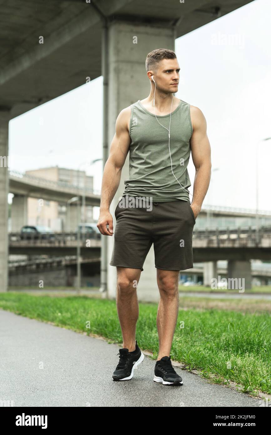 Homme beau avec des écouteurs. Écouter de la musique pendant un entraînement physique dans la rue. Banque D'Images