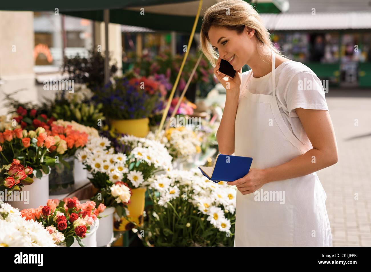 Femme fleuriste prenant l'ordre par téléphone dans son petit magasin de fleurs Banque D'Images