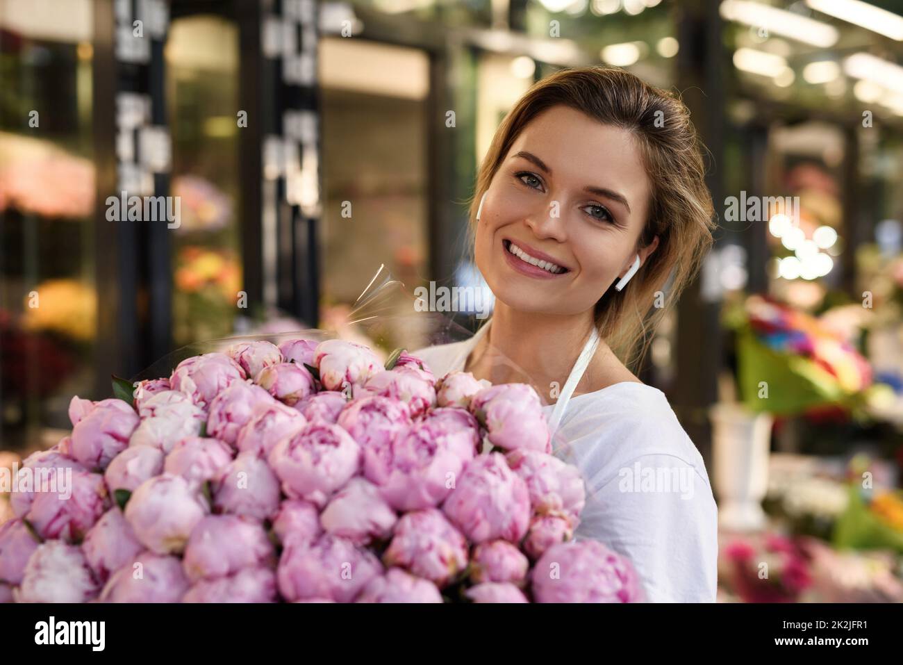 Femme fleuriste avec un tas de fleurs de pivoine rose dans son petit magasin de fleurs Banque D'Images