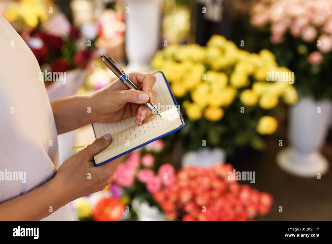 Femme fleuriste prenant des notes dans son carnet Banque D'Images