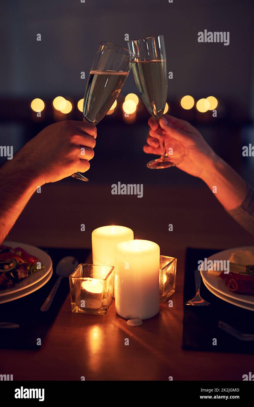 Heres pour nous et notre avenir. Photo d'un couple méconnaissable ayant un toast festif au cours d'un dîner aux chandelles le soir. Banque D'Images