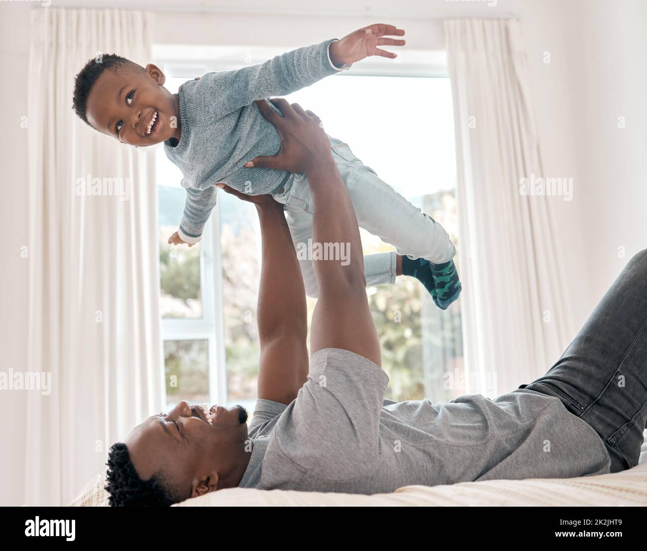 Plus élevé, plus élevé. Photo courte d'un adorable petit garçon jouant avec son père sur un lit à la maison. Banque D'Images