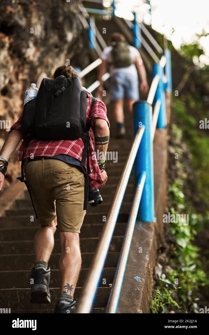 Pour atteindre le sommet. Vue arrière de deux hommes grimpant les escaliers tout en faisant de la randonnée dans les montagnes. Banque D'Images