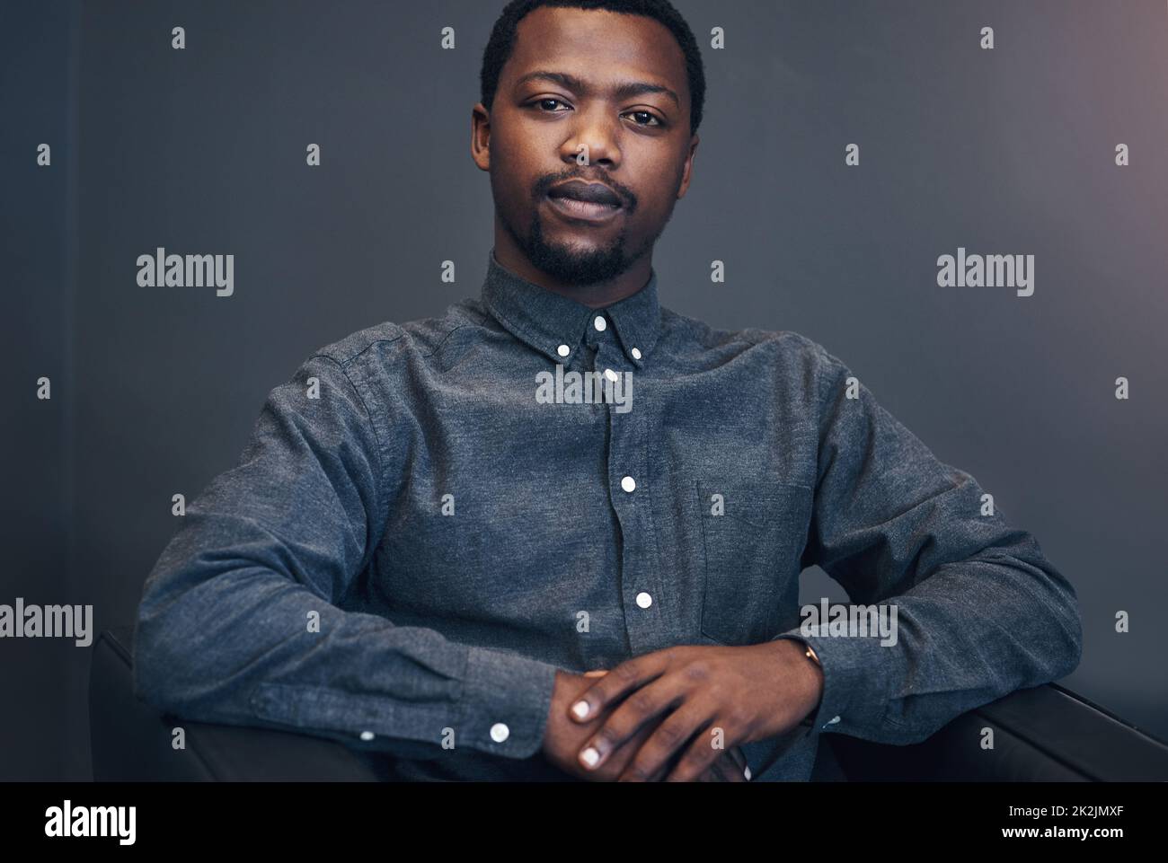 Je peux vous parler de la création d'entreprise. Portrait court d'un beau jeune homme architecte assis sur un canapé dans un bureau moderne. Banque D'Images