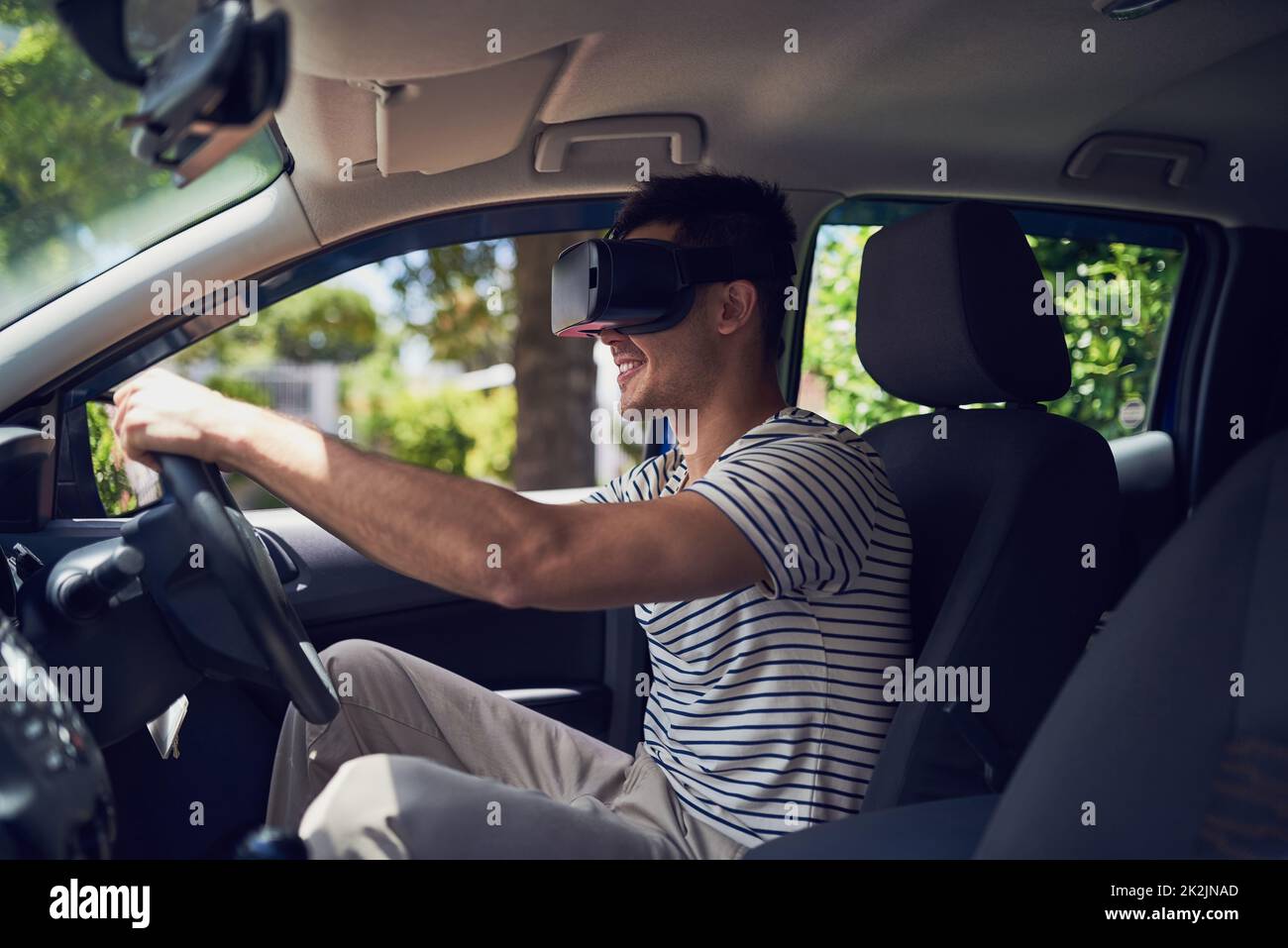 Prenons cette nouvelle technologie pour un essai routier. Photo d'un jeune homme heureux conduisant une voiture tout en portant un casque de réalité virtuelle. Banque D'Images