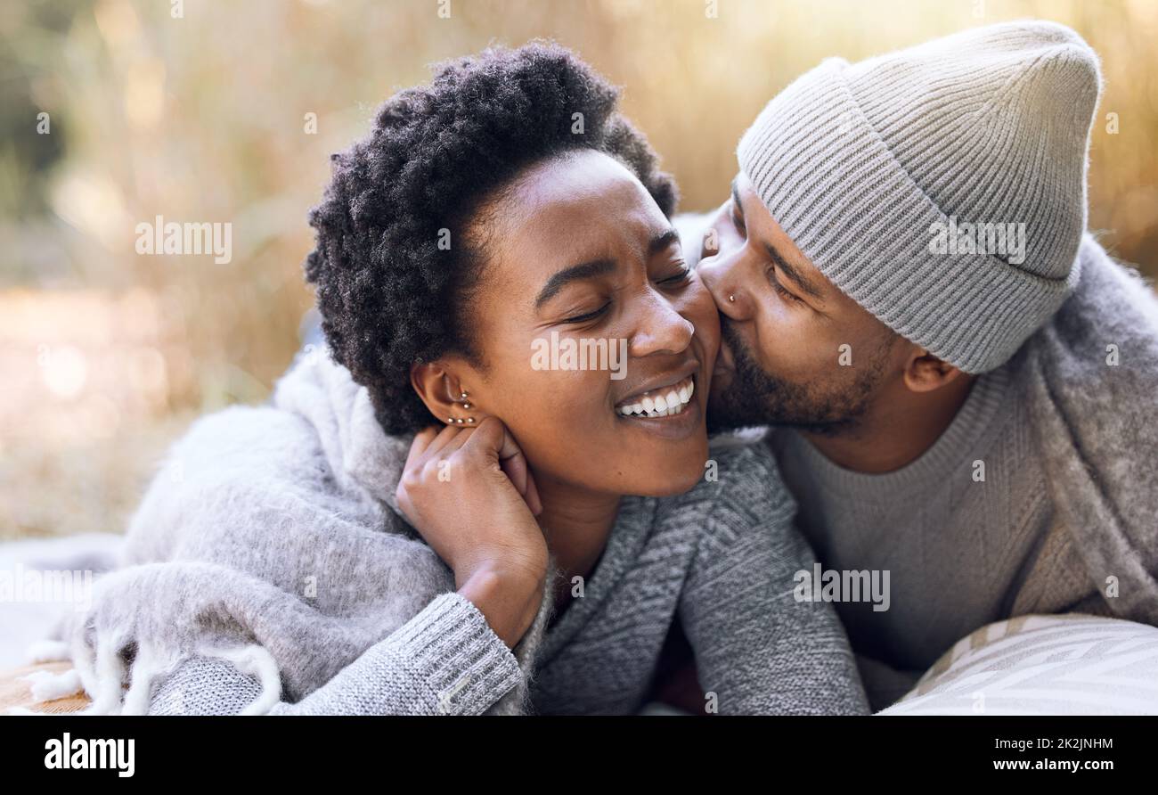Vos joues sont comme des oreillers. Photo d'un jeune homme embrassant sa petite amie lors d'un voyage en camping. Banque D'Images