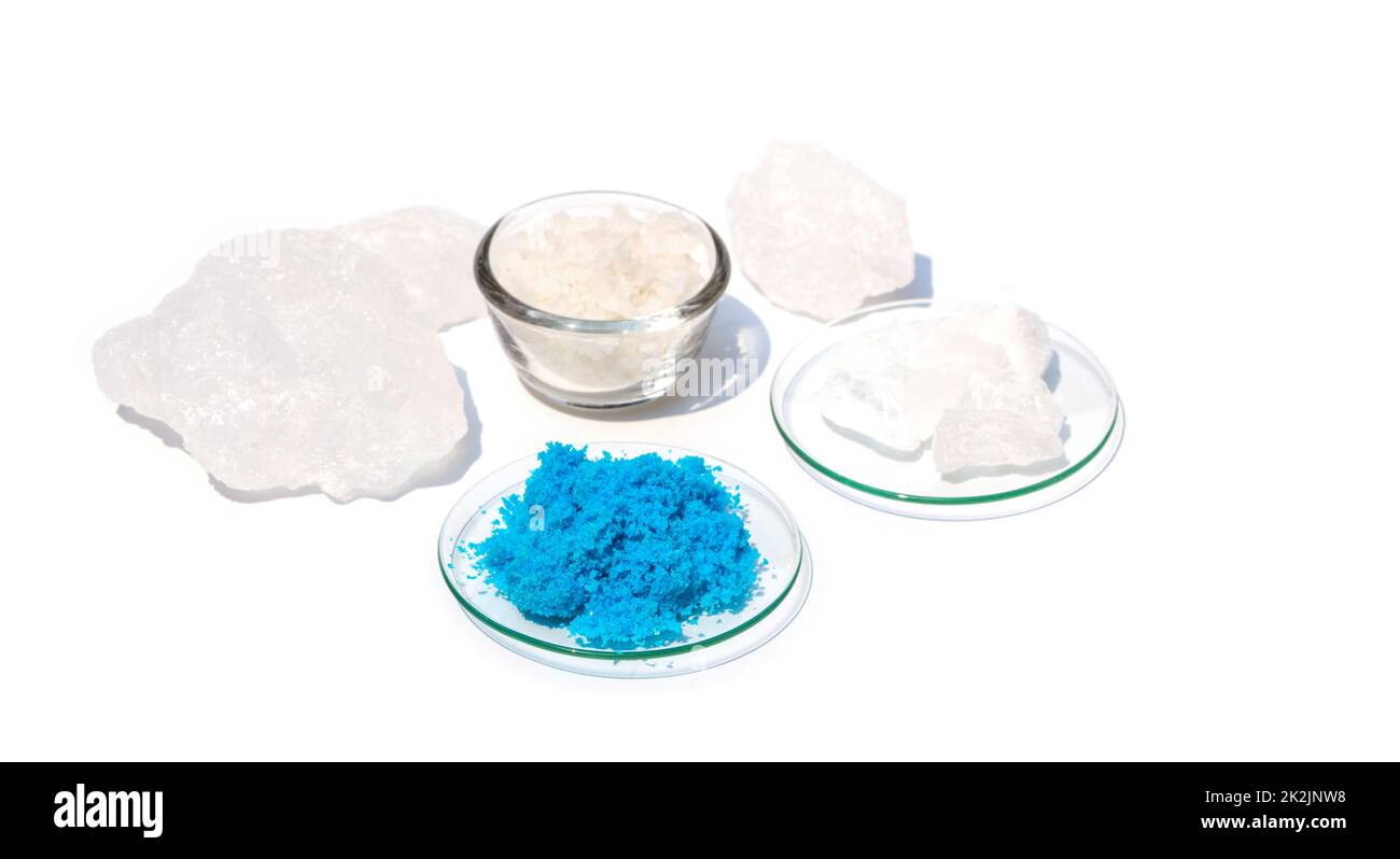Gros plan sur une table de laboratoire blanche. Sulfate de cuivre(II) dans le verre de surveillance chimique. Le cristal d'alun et le sel de Flake ont été placés plus loin. Banque D'Images