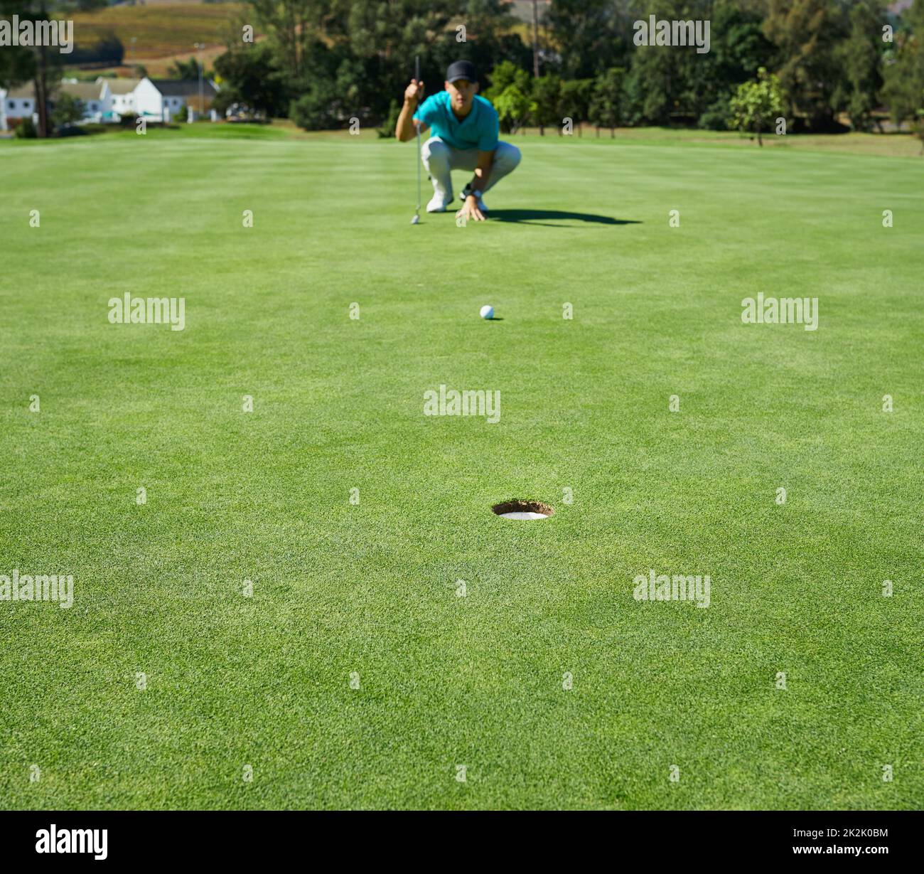 Pour un look simple. Photo d'un jeune homme concentré en attente de la balle d'or qu'il vient de frapper pour aller dans un trou à l'extérieur sur un terrain de golf. Banque D'Images