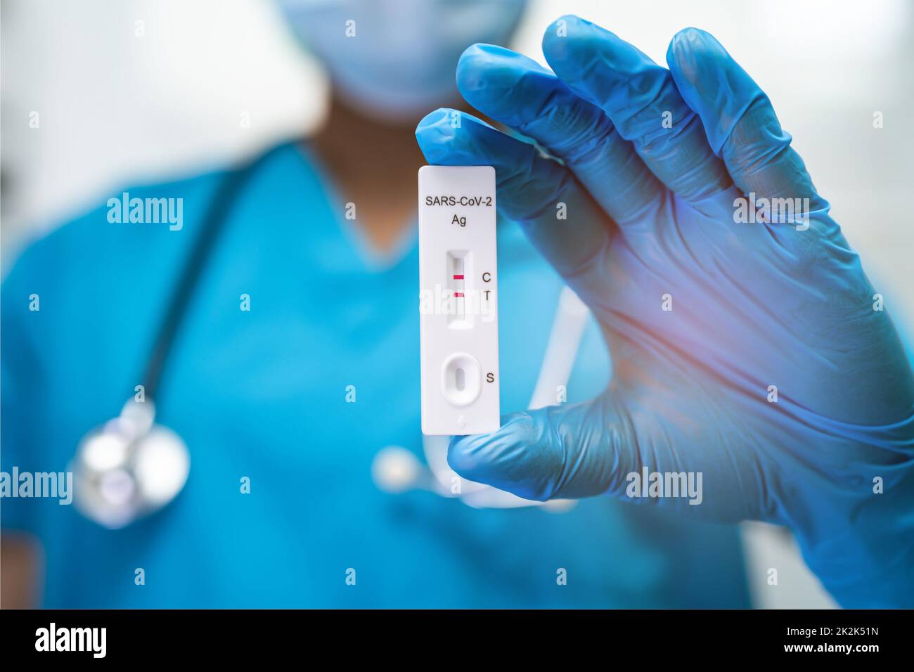 Un médecin asiatique en costume d'EPI montre un résultat de test positif avec de la salive A. Banque D'Images