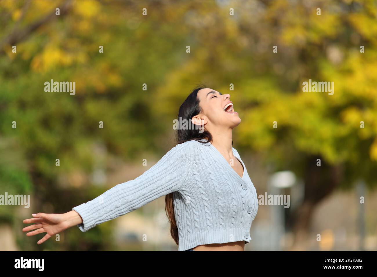 Une femme excitée criant les bras dans un parc Banque D'Images