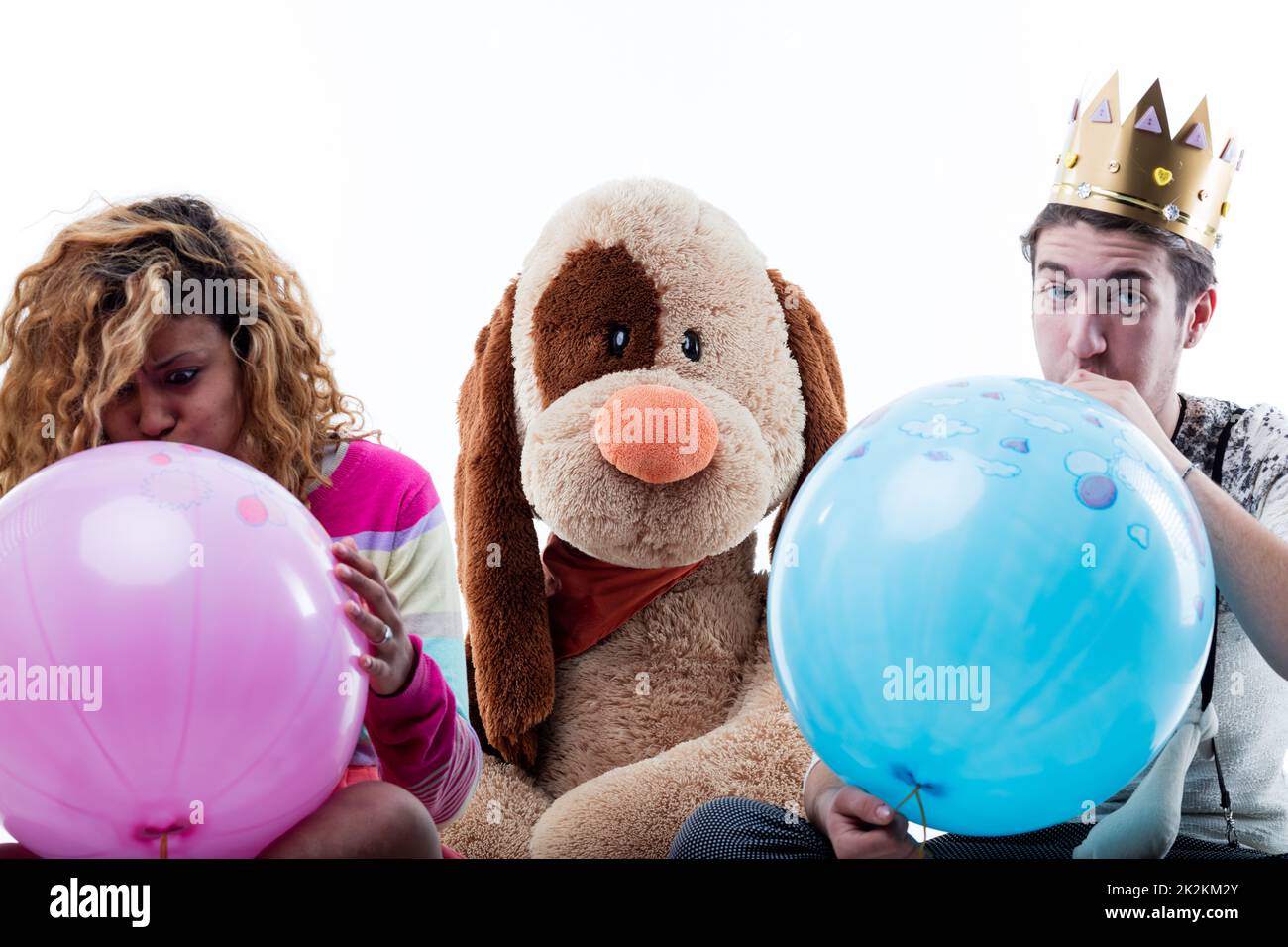 Jeune femme avec homme soufflant de gros ballons Banque D'Images