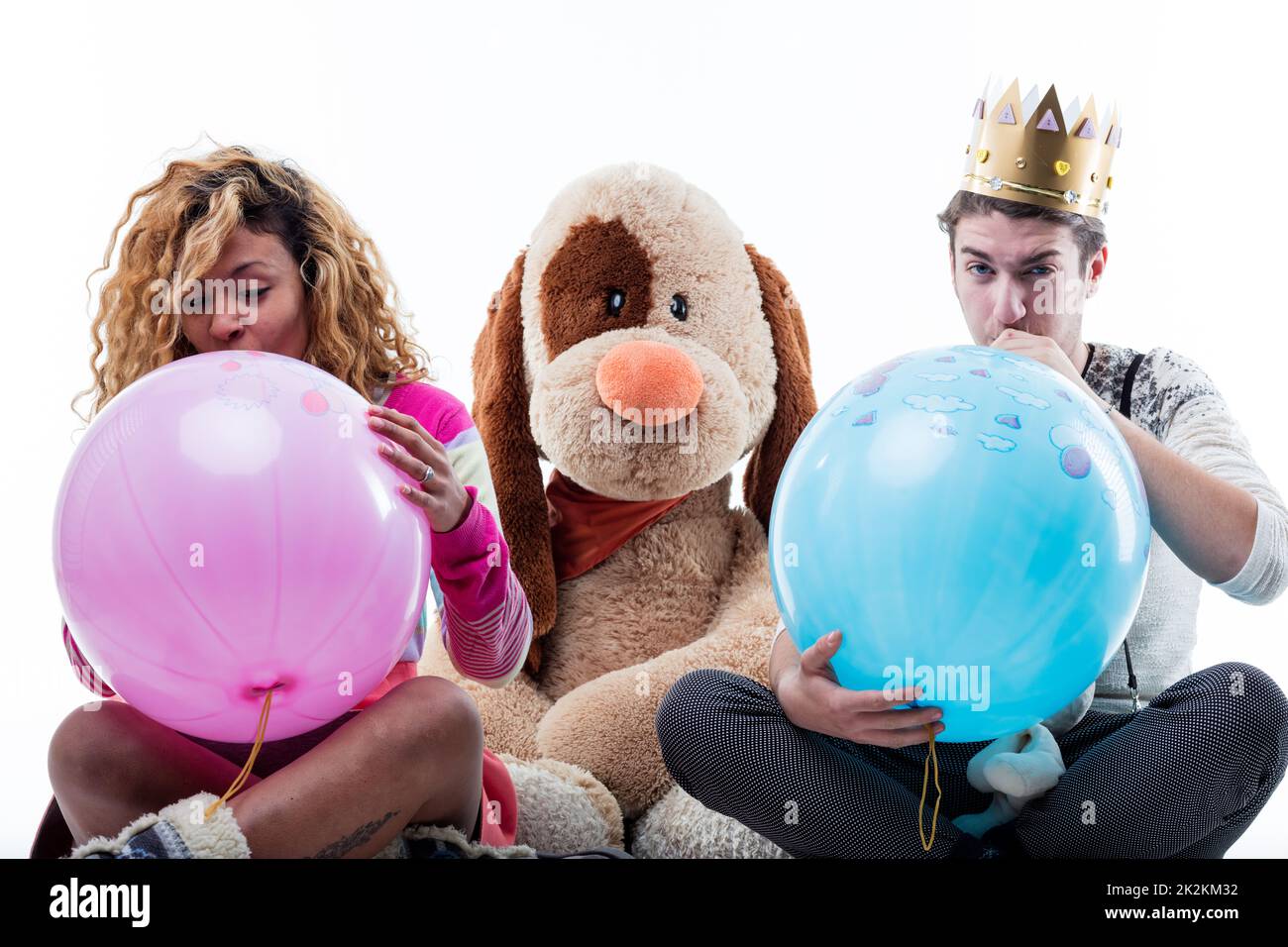 Jeune femme avec homme soufflant de grands ballons de partie Banque D'Images