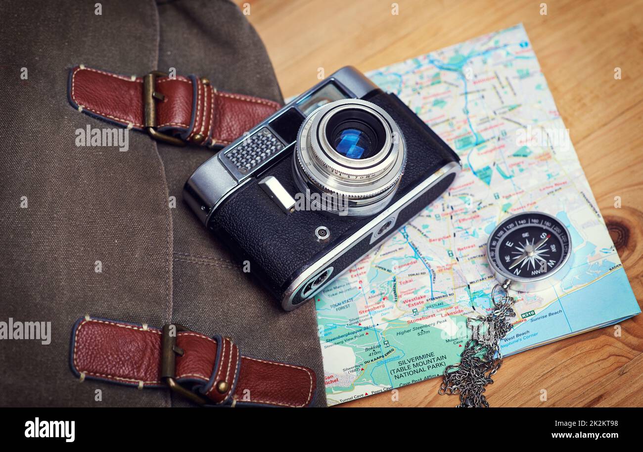 Faites de la vie une aventure audacieuse. Un appareil photo, une carte, une boussole et un sac sur une table en bois. Banque D'Images