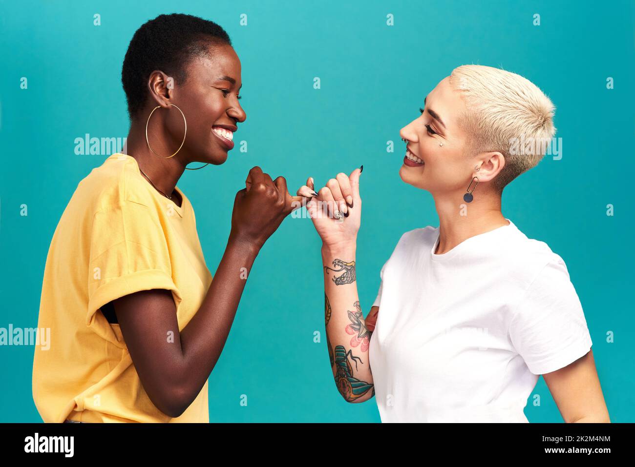 Vous pouvez compter sur moi.Studio de deux jeunes femmes reliant leurs doigts sur un fond turquoise. Banque D'Images