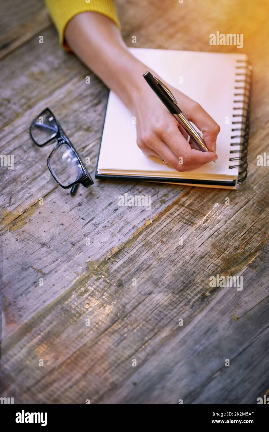 C'est une toile vierge pour ses pensées. Photo rognée d'une femme assise à une table et écrivant dans son bloc-notes. Banque D'Images