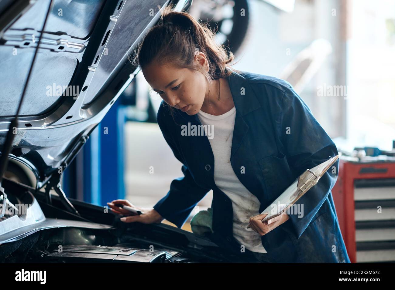 Shell vous donne la meilleure et la moins chère solution pour vos problèmes de voiture. Photo d'une mécanicien travaillant sur une voiture dans un atelier de réparation automobile. Banque D'Images