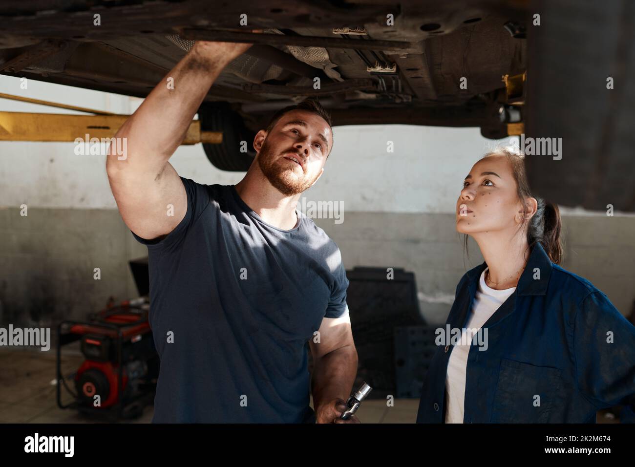 Le service de premier ordre est notre principale automobile. Photo de deux mécaniciens travaillant ensemble sous une voiture soulevée. Banque D'Images