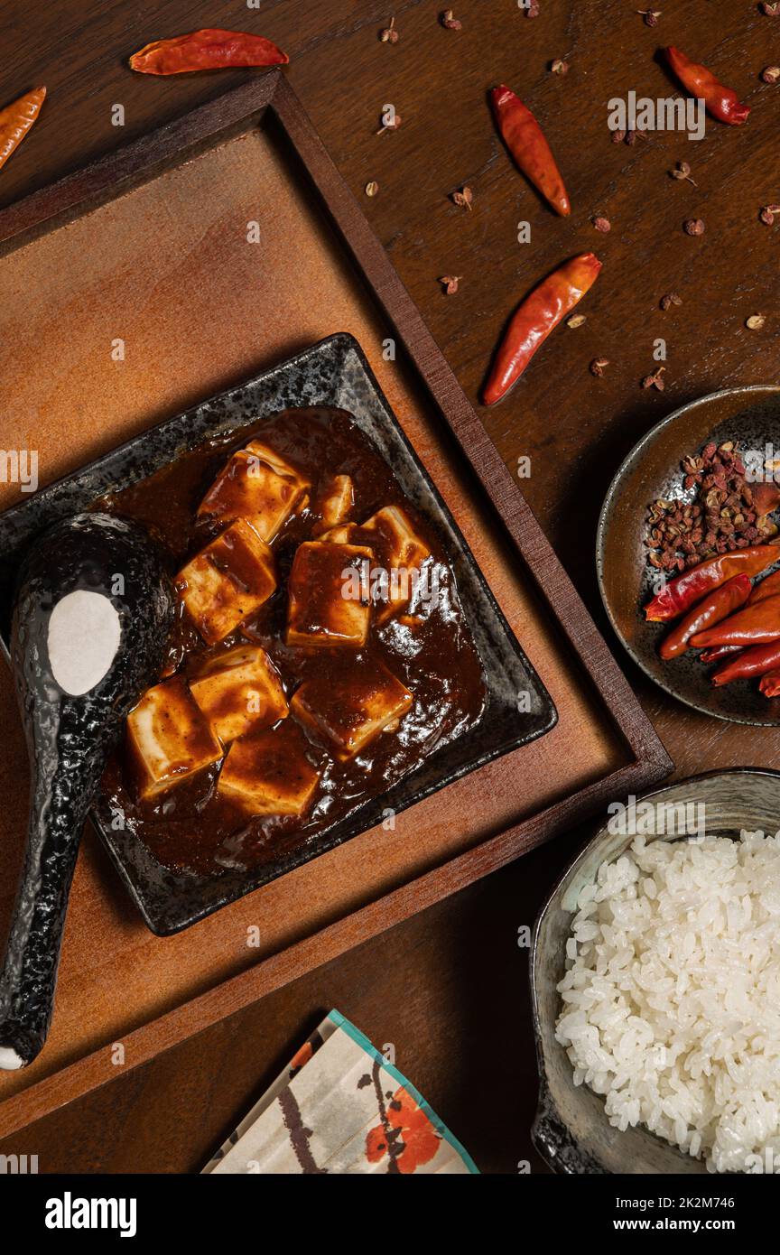 Cuisine chinoise traditionnelle, mapo tofu (tofu épicé chaud) avec riz, décorations anciennes et épices (poivre, piment et anis étoilé). Banque D'Images