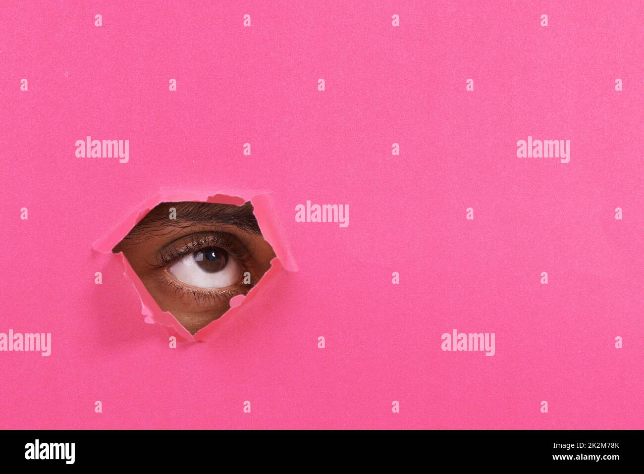 Je vois quelque chose là-haut... Une vue d'un oeil de homme regardant à travers un trou dans un papier coloré. Banque D'Images