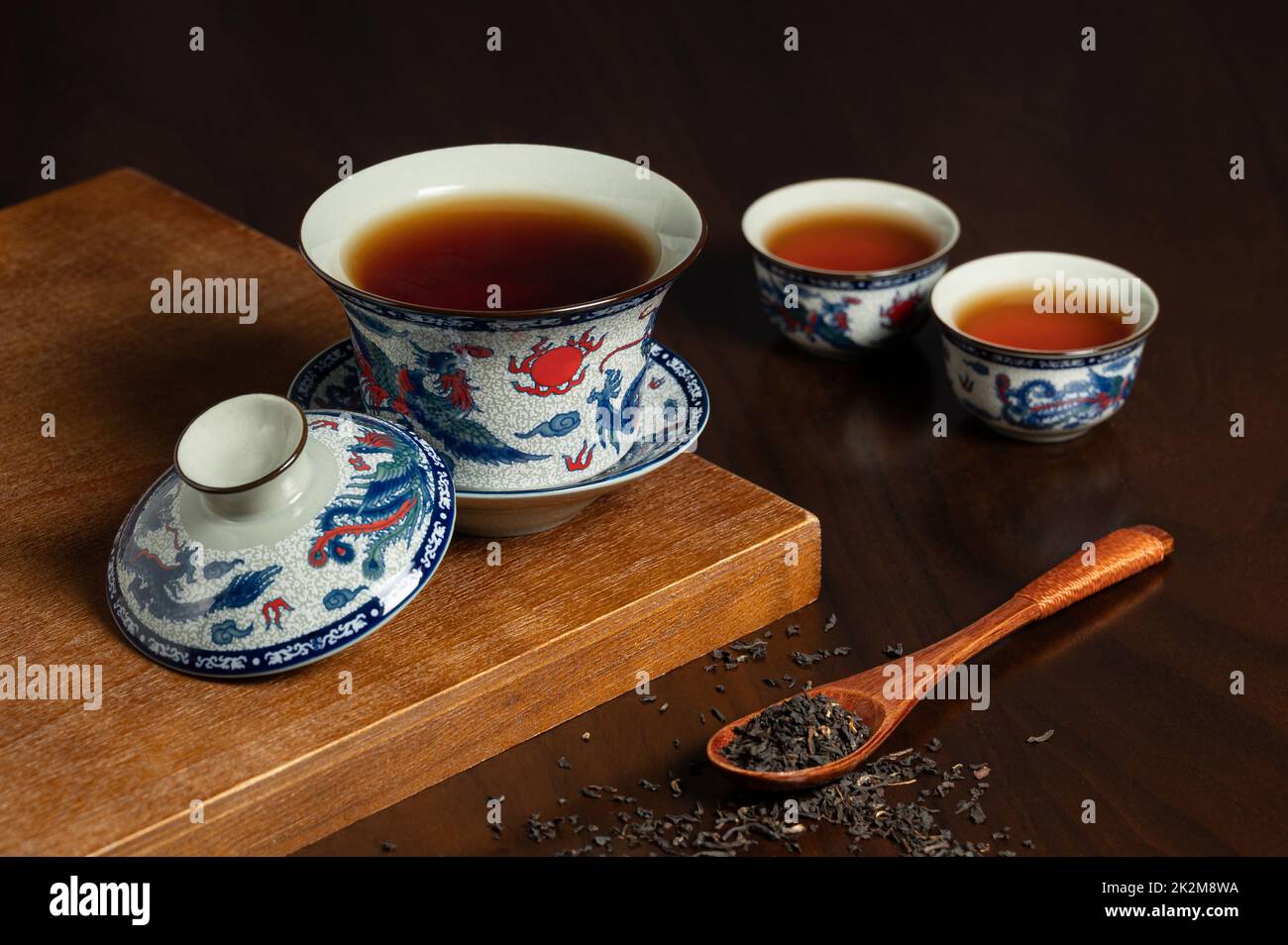tasse de thé traditionnelle chinoise en porcelaine et feuille de thé sur un panneau ancien en bois Banque D'Images