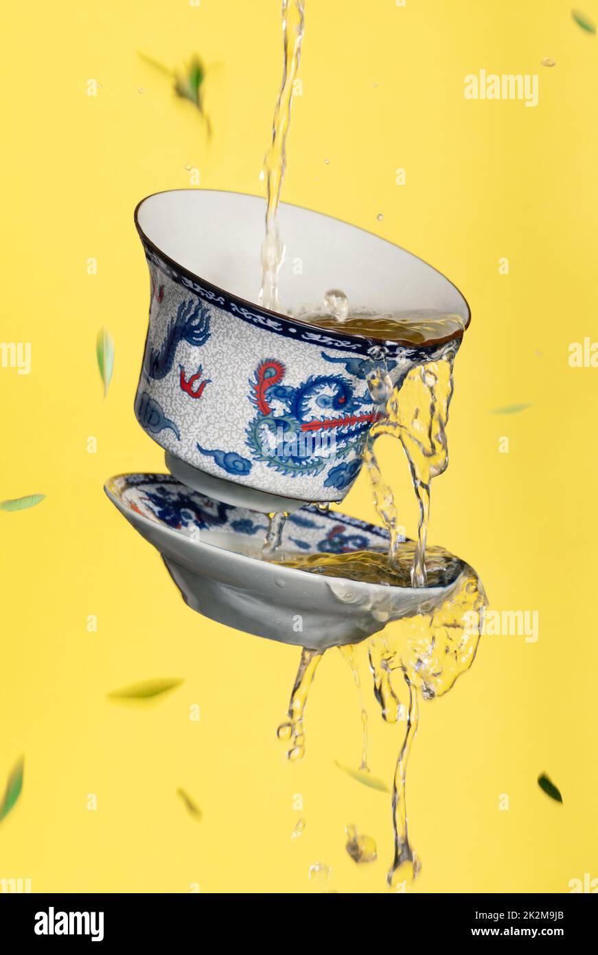 tasse de thé chinois flottant avec thé vert chaud, congé de thé et fond jaune Banque D'Images